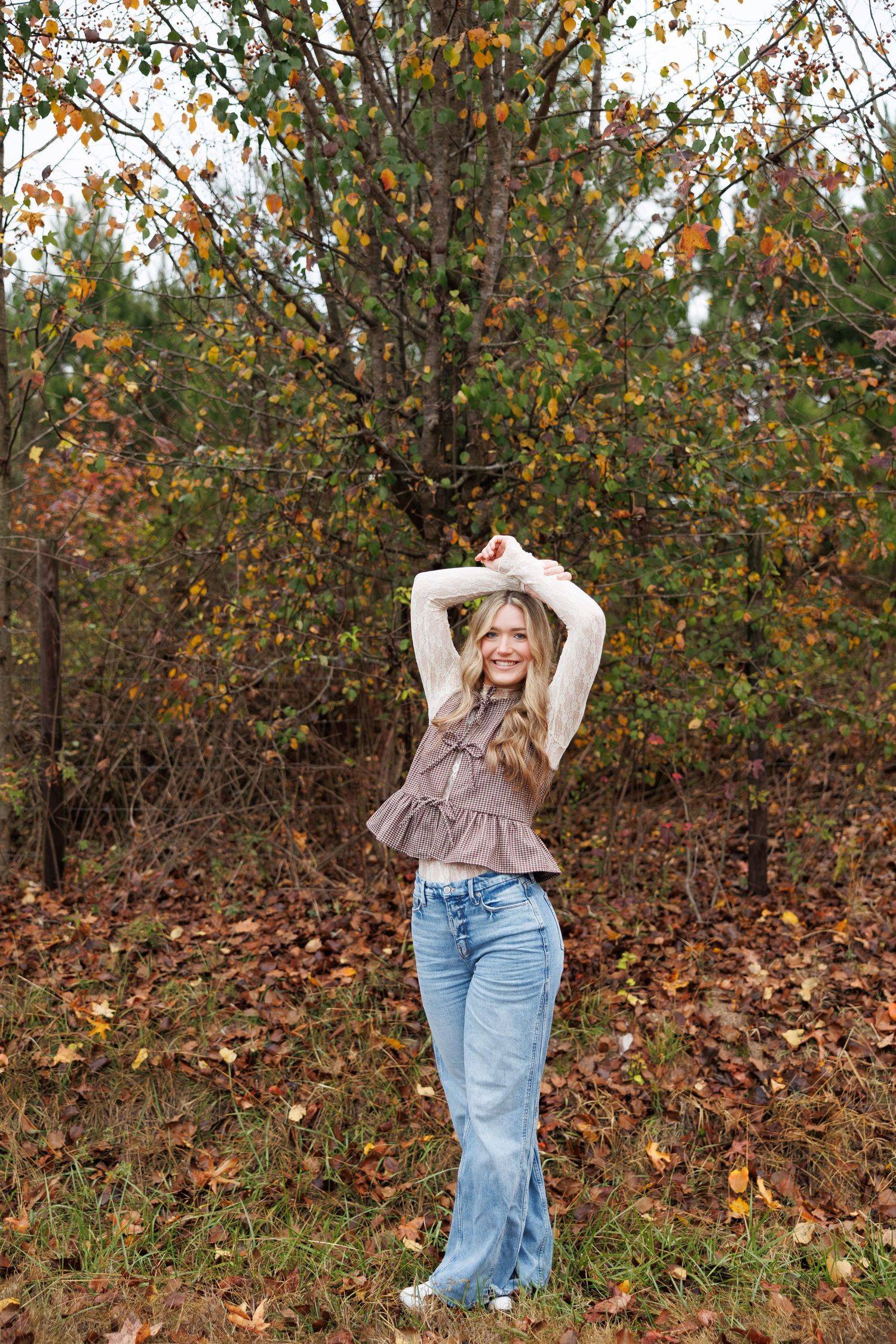 Fashion pose in autumn setting with bell bottom jeans and vintage-style top.