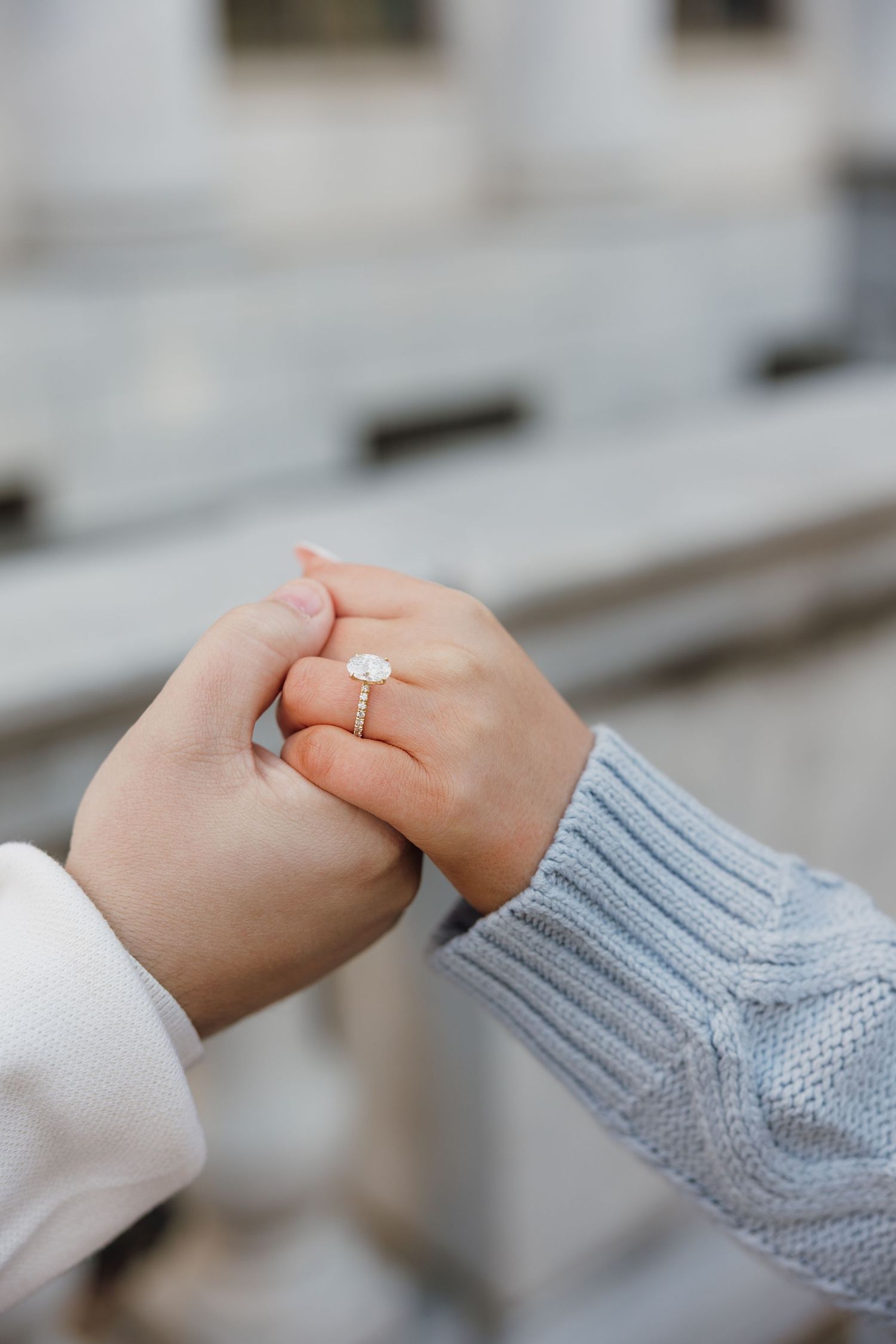 Close up of hands clasping together with one wearing a gray knit sweater sleeve.