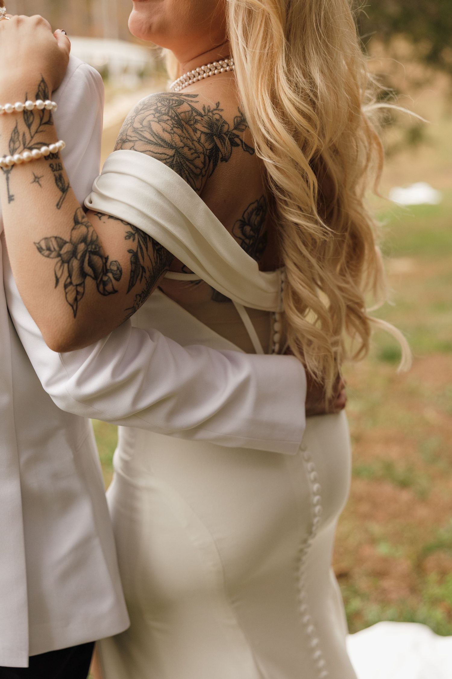 Elegant bridal details showing pearl necklace and intricate shoulder tattoo design.