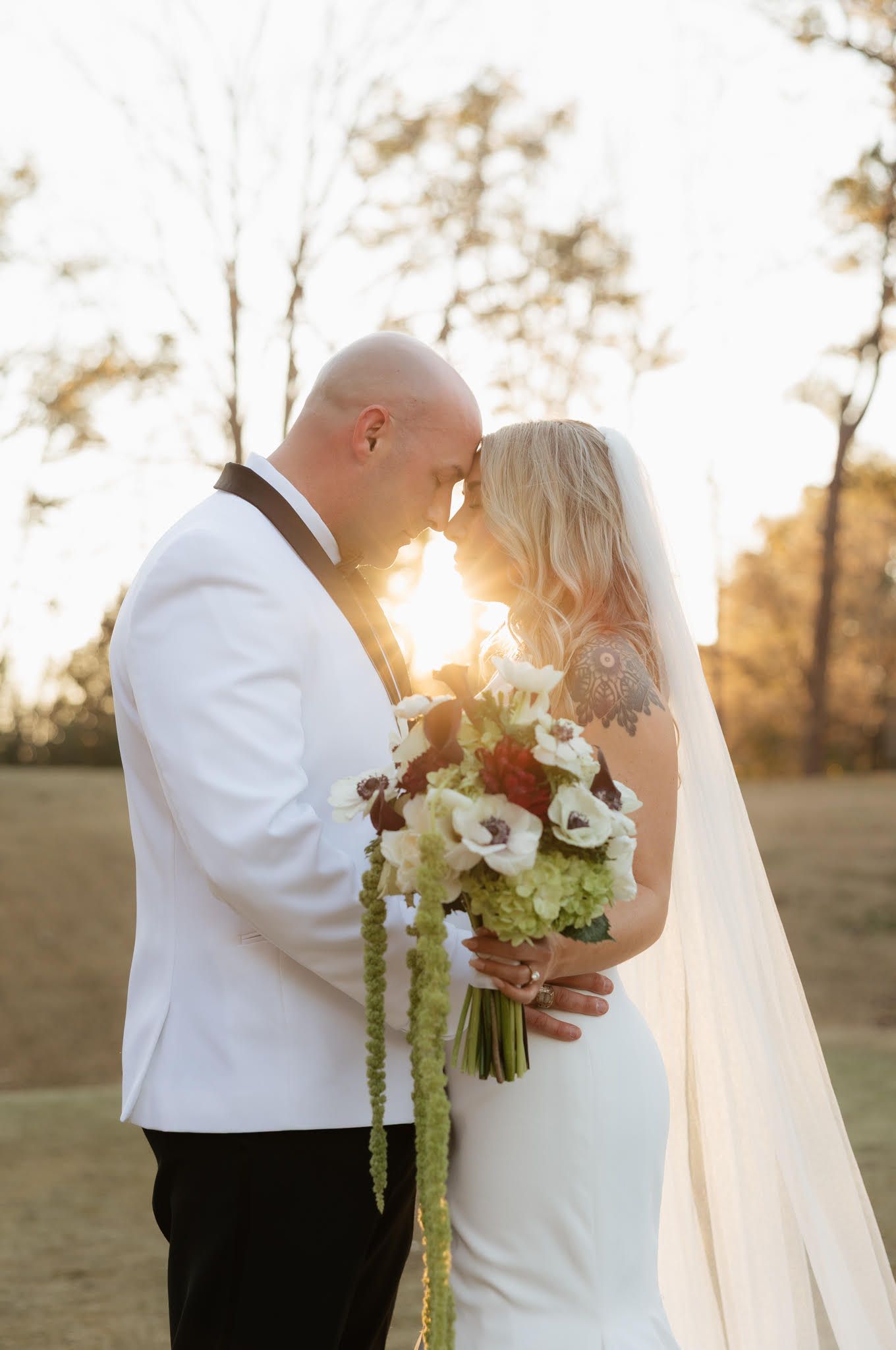 Golden hour wedding portraits with sunlight streaming through as couple shares intimate moment.