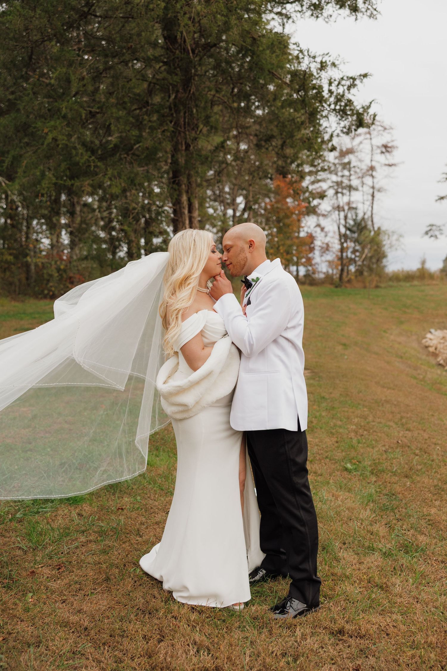 Romantic wedding photo of a couple embracing outdoors with flowing veil.