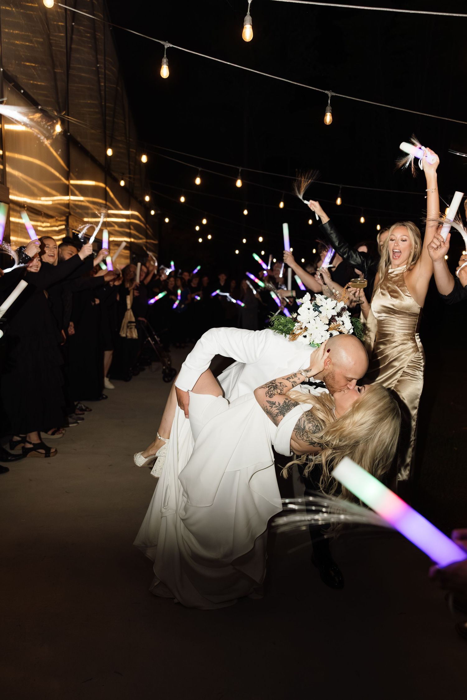 Wedding celebration with guests dancing under string lights at night.