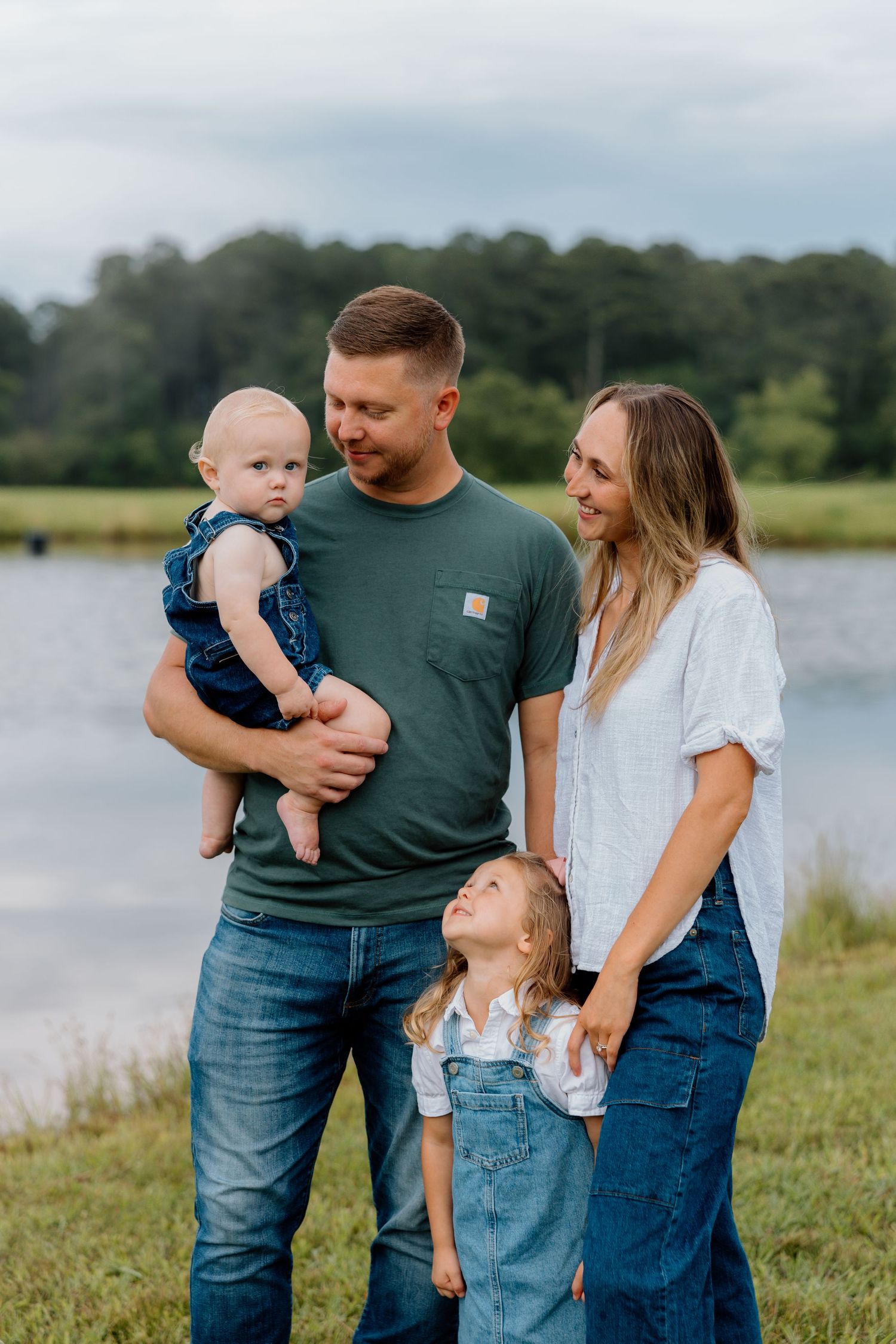 A family shares joyful moments together by a serene lake on a sunny afternoon.