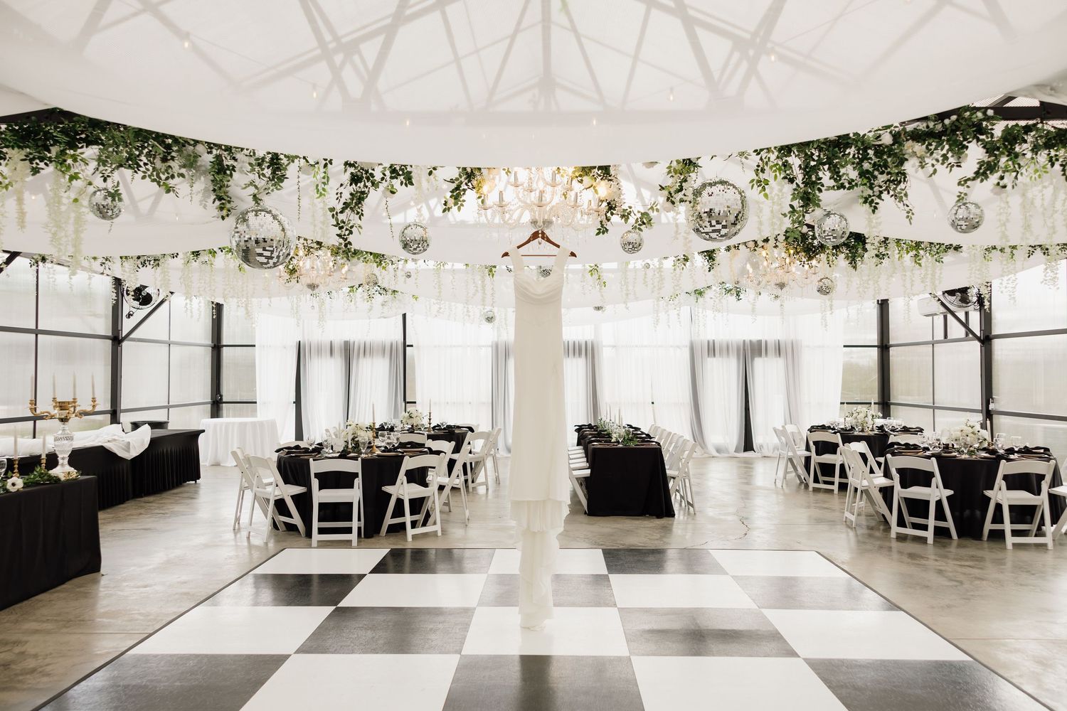 Elegant white wedding reception venue with draped fabric ceiling and round tables set for a celebration.