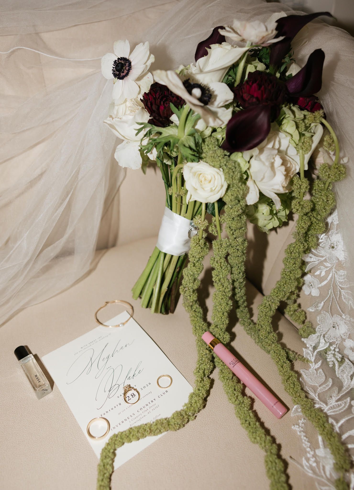 Wedding detail flatlay with white florals, green amaranthus, and elegant stationery on neutral background.