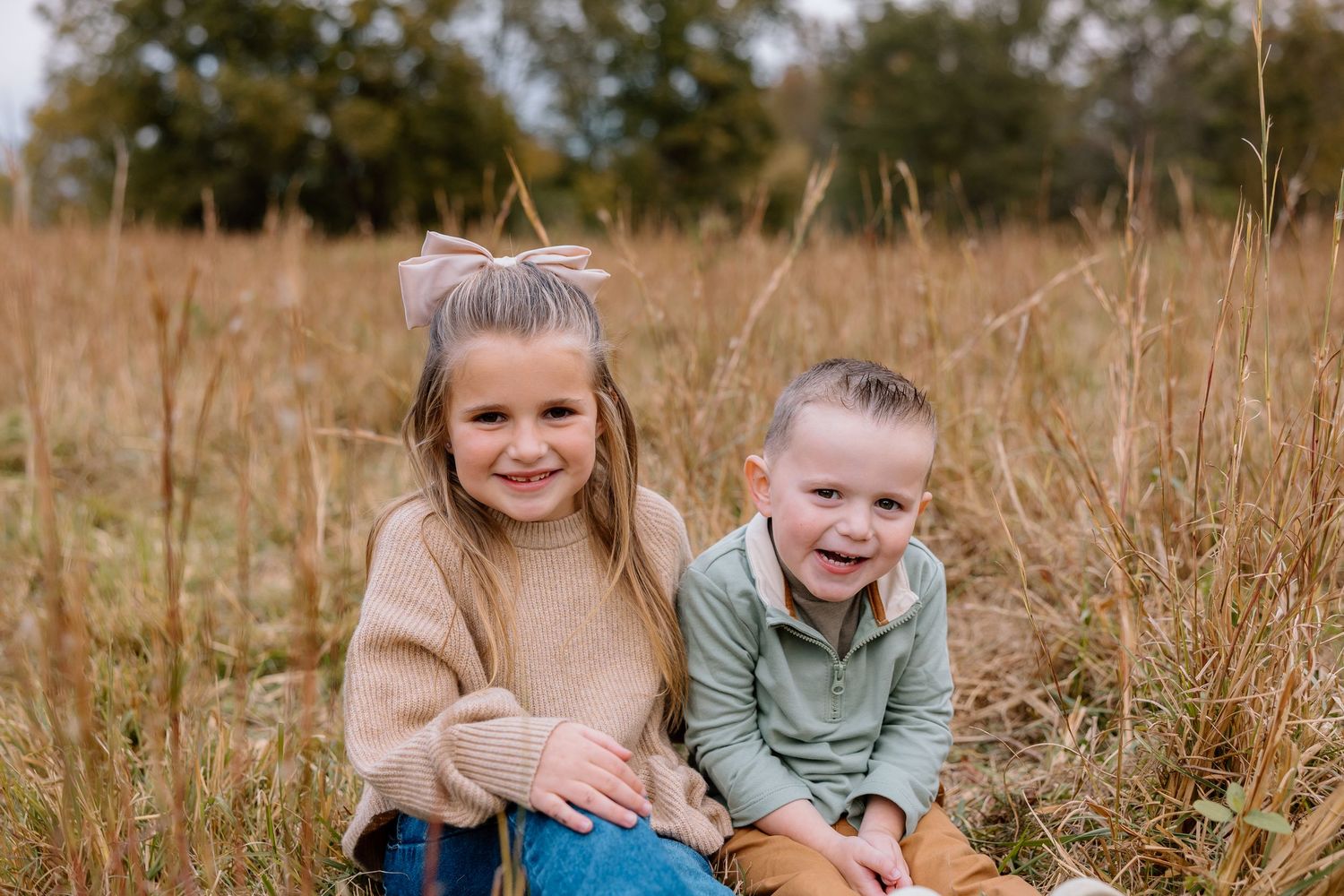 Children playing and laughing together in a golden autumn field during a sunny afternoon.