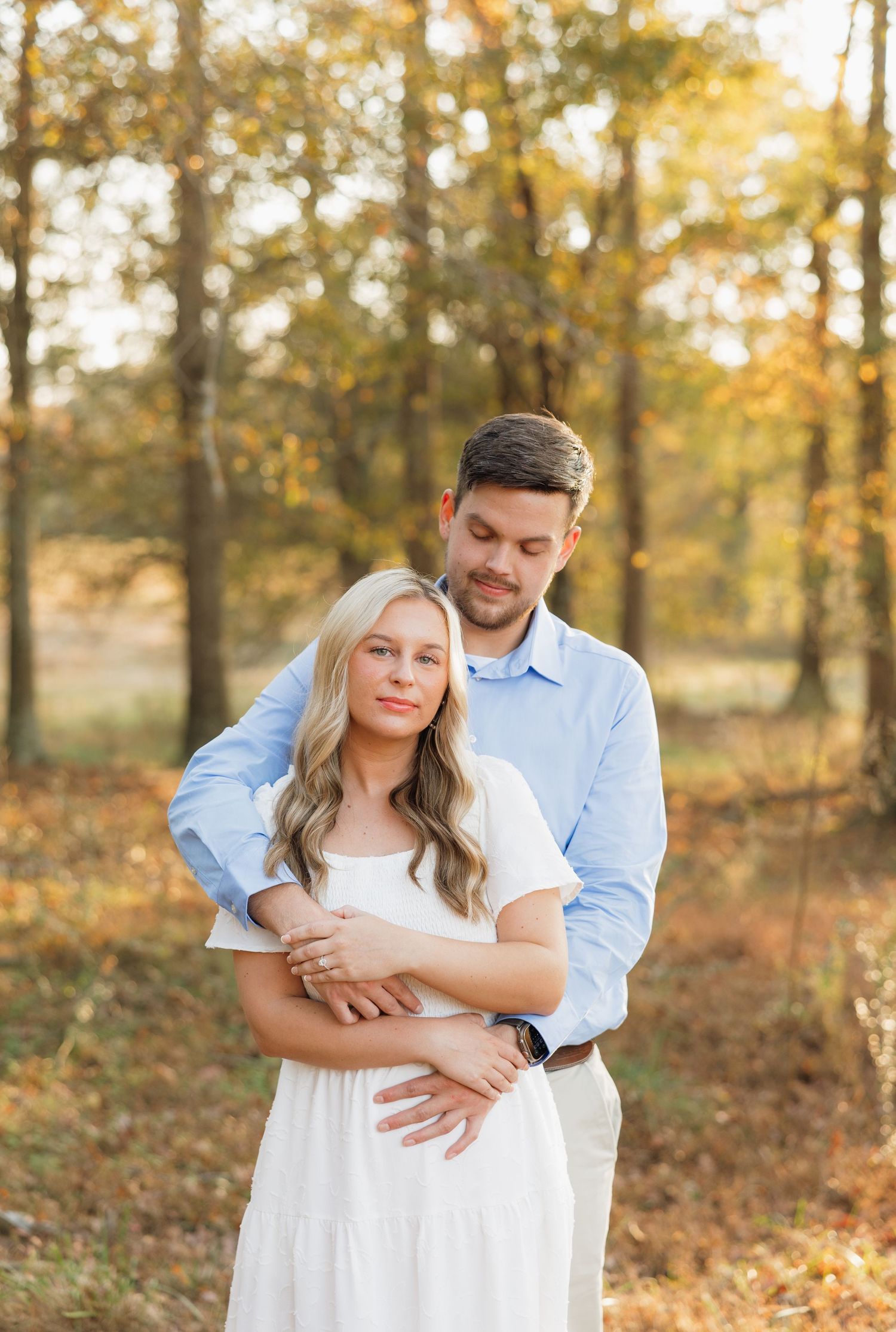 Couple embracing in a golden autumn forest during sunset.