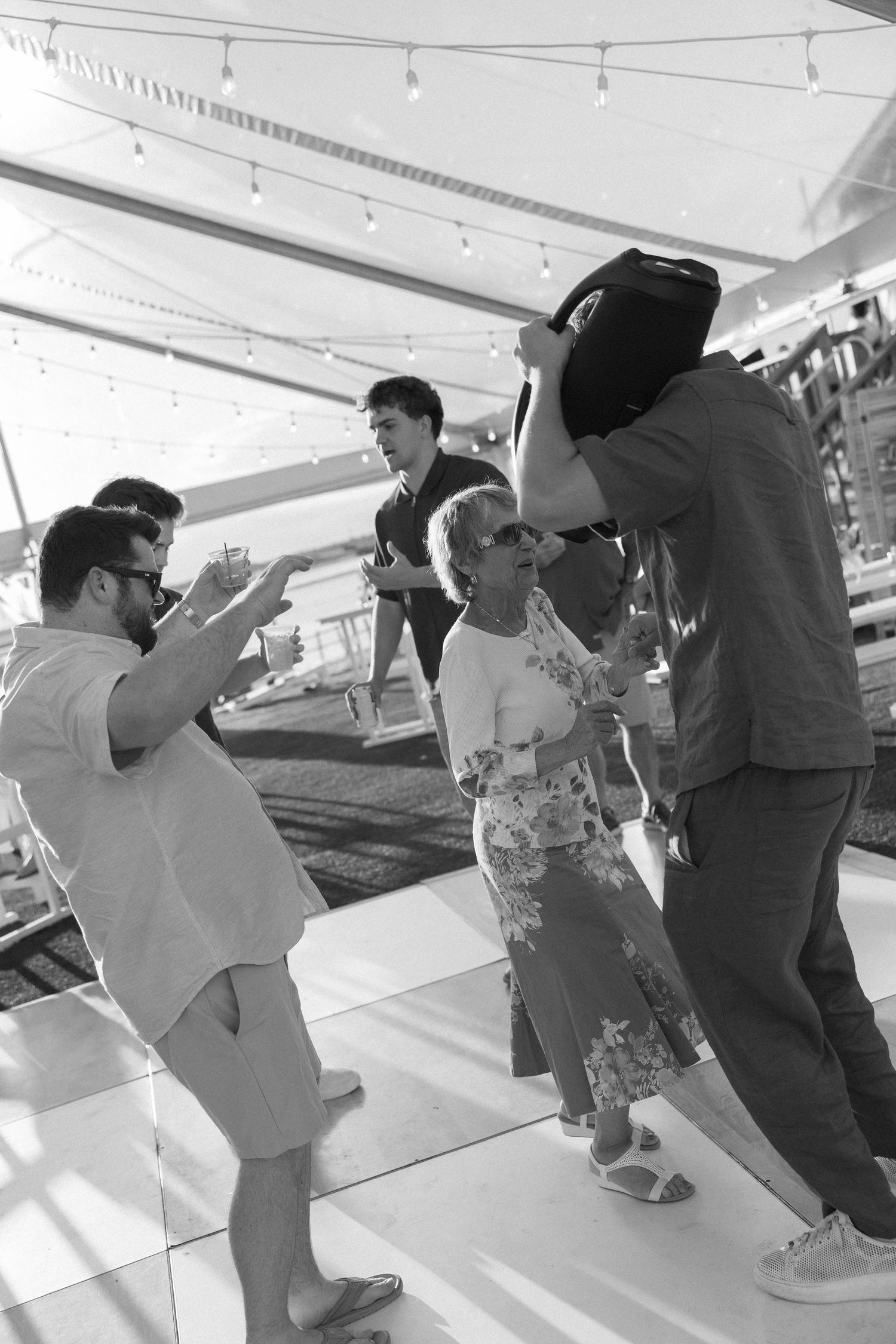 Black and white photo of guests dancing and celebrating on a dance floor at an outdoor event.