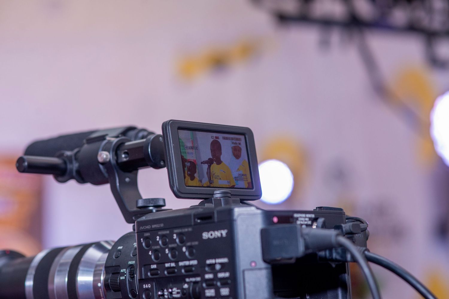 Sony professional video camera with a monitor displaying two people being filmed at an event.