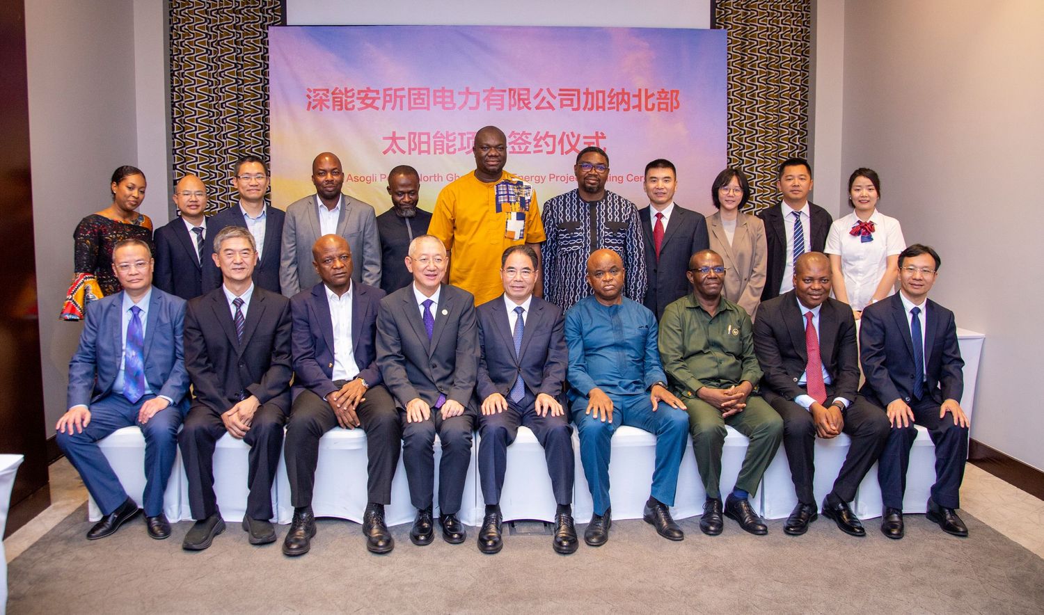 Group photo of African and Asian business delegates at a formal solar energy contract signing ceremony indoors.
