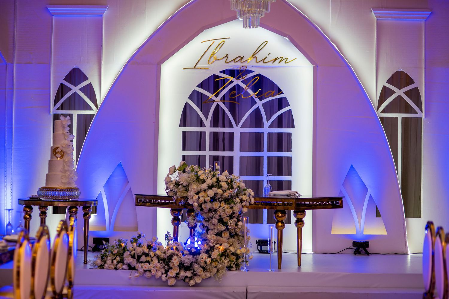Elegant wedding reception venue with Ibrahim signage, floral arrangements and wedding cake.