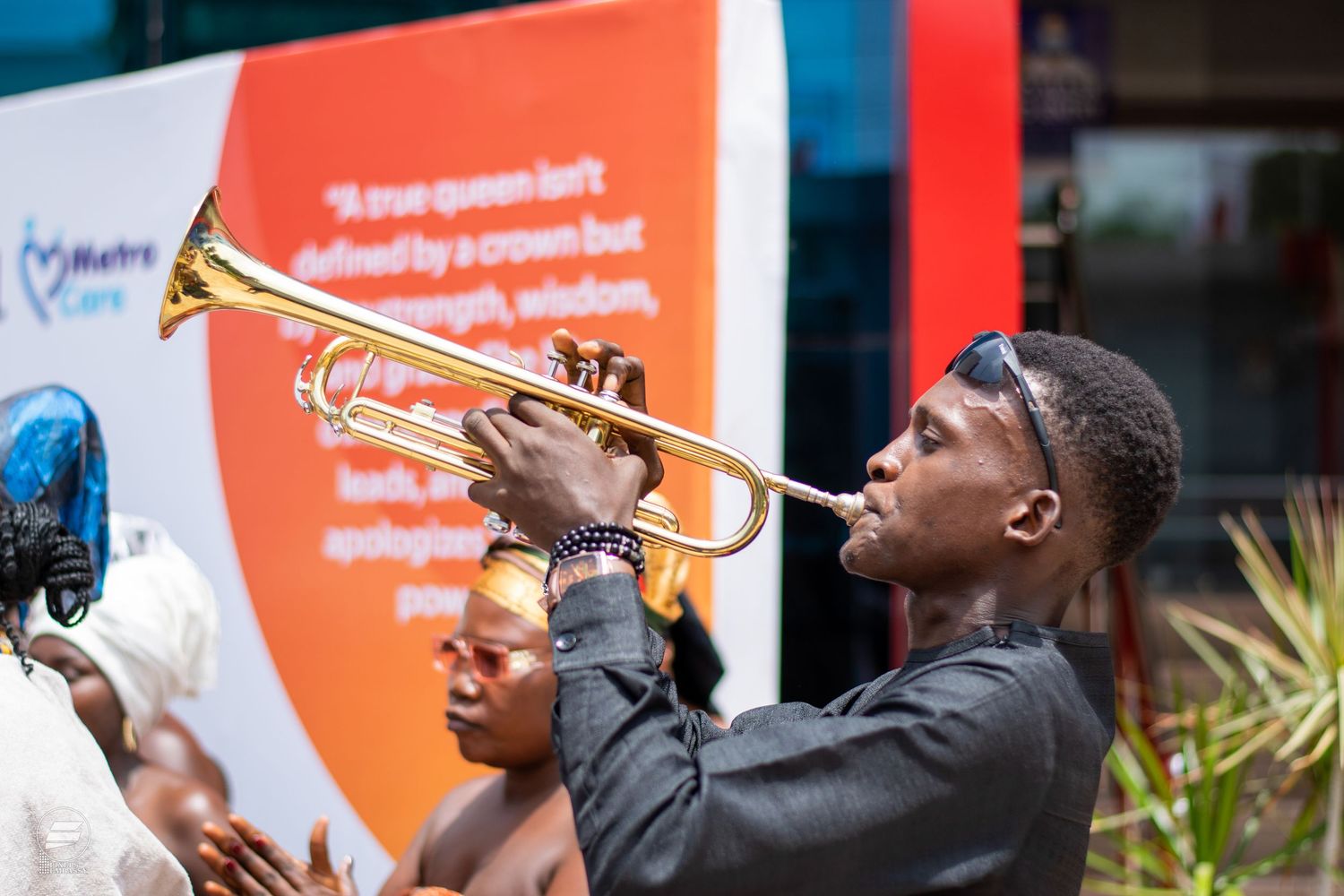 Young African man playing trumpet at an outdoor cultural event in Ghana.
