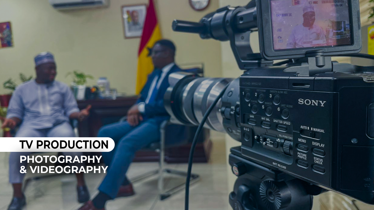 Professional TV production setup with a Sony camera filming an interview in an office setting.
