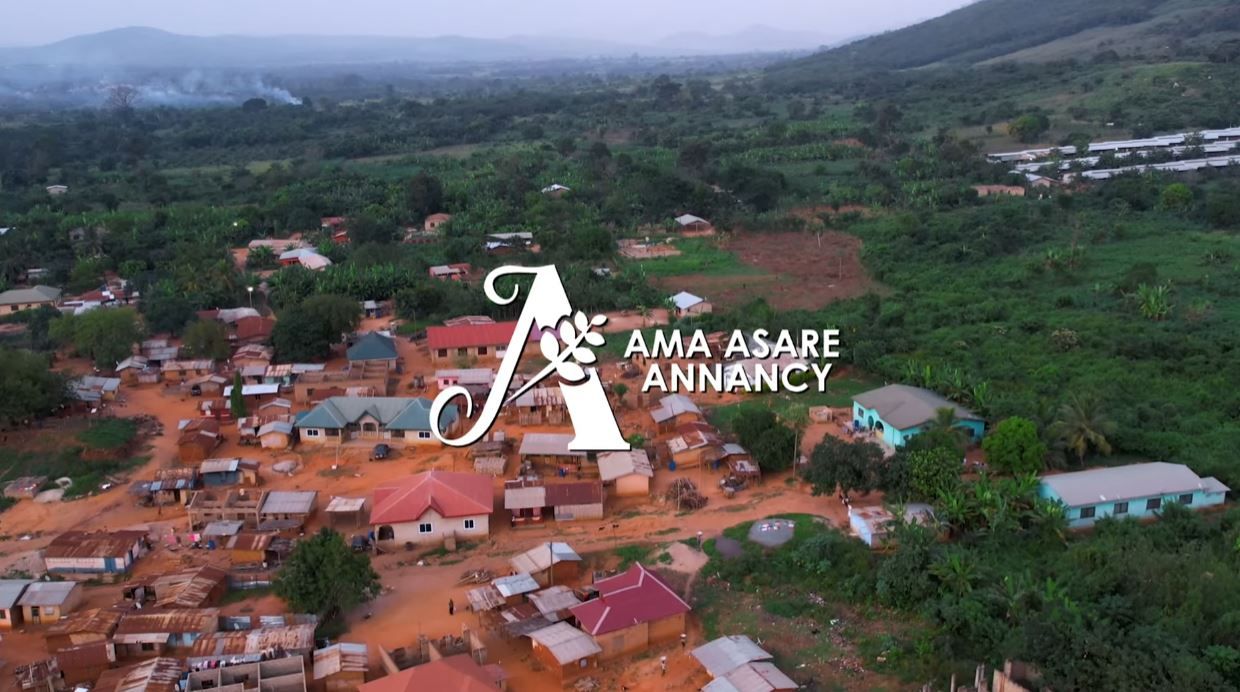 Aerial drone view of Ghanaian village with red rooftops and green landscape.