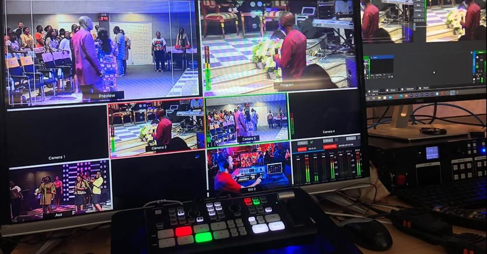 A professional video production setup with multiple monitor screens showing live event footage and a mixing console.