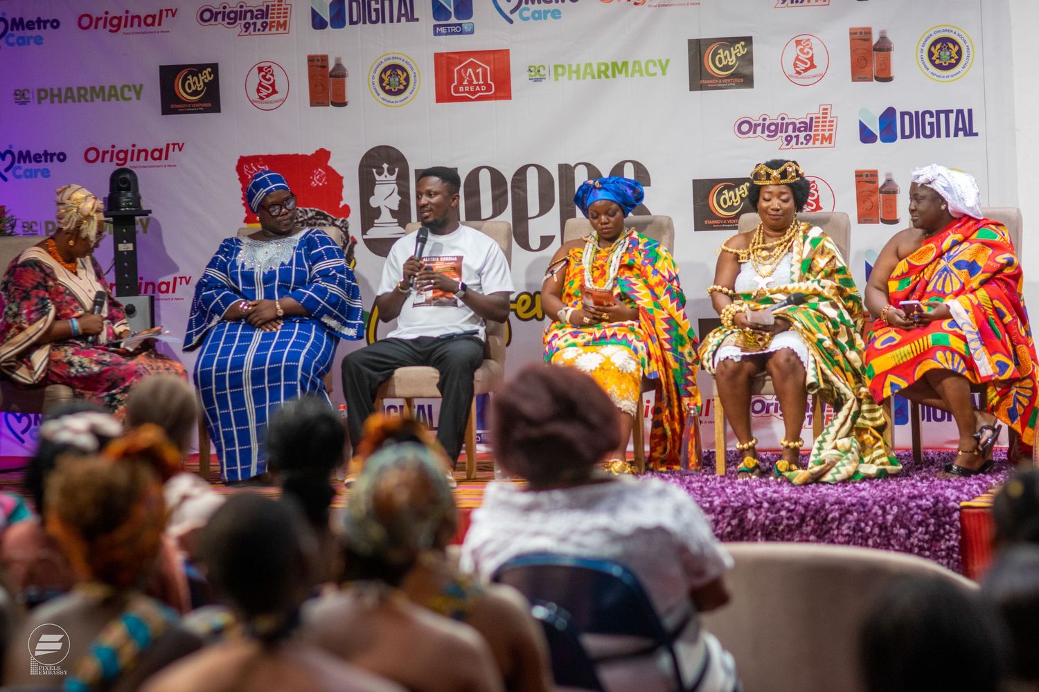 Panel of five speakers in traditional African attire at a cultural conference.