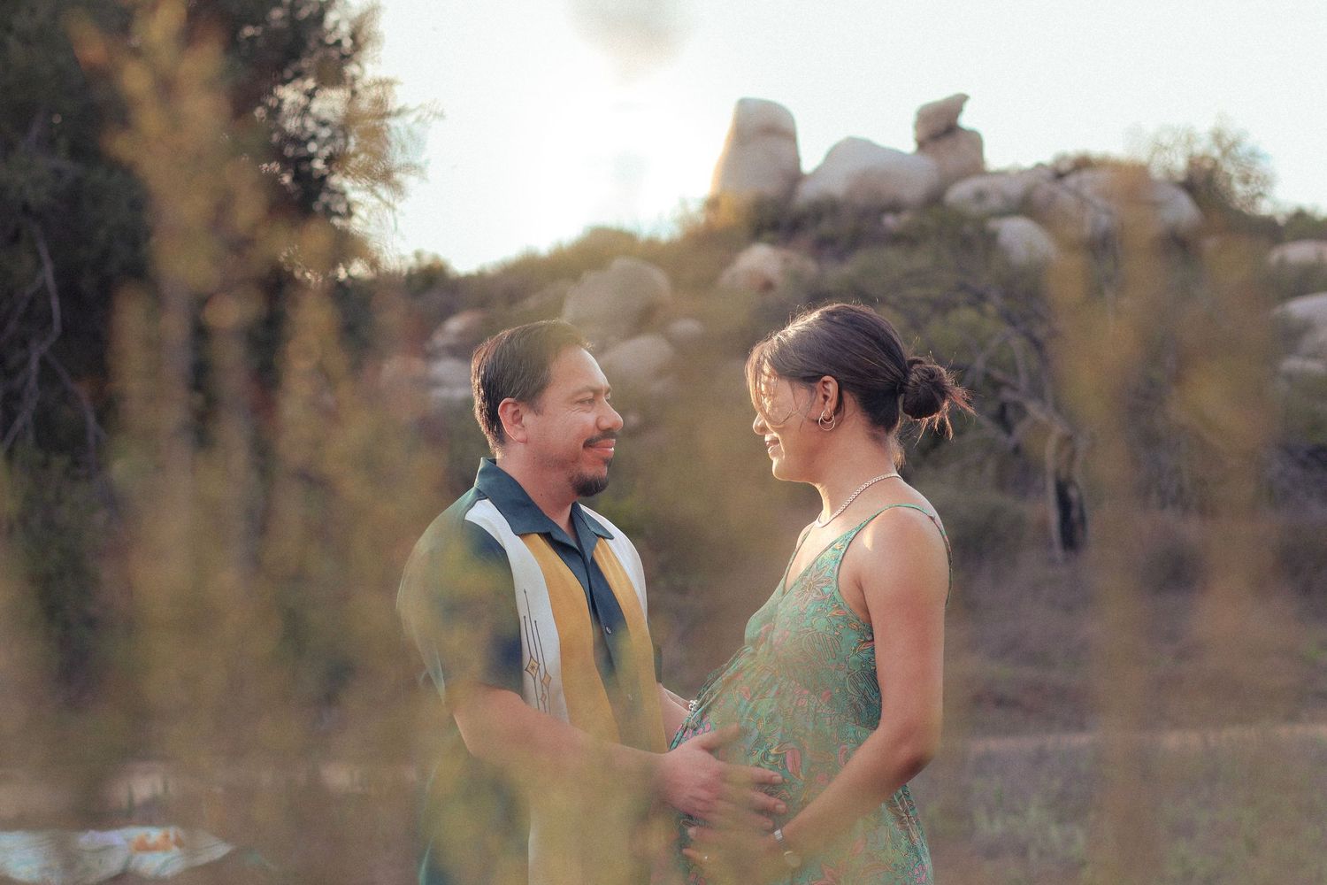 Couple embracing in open field in Murrieta with warm tones.
