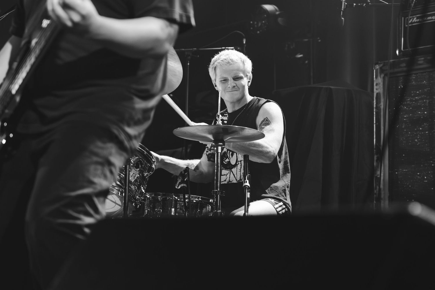 Black and white photo of drummer playing cymbals on stage during live rock concert performance.