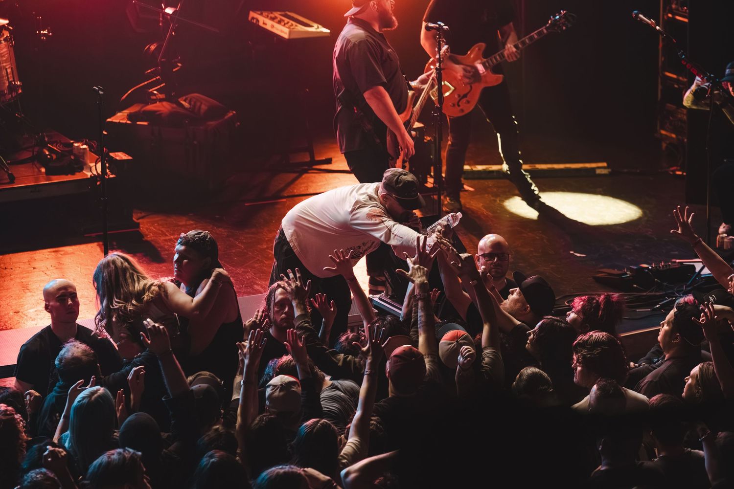 Vocalist leaning into the crowd during an energetic live concert under warm stage lighting.