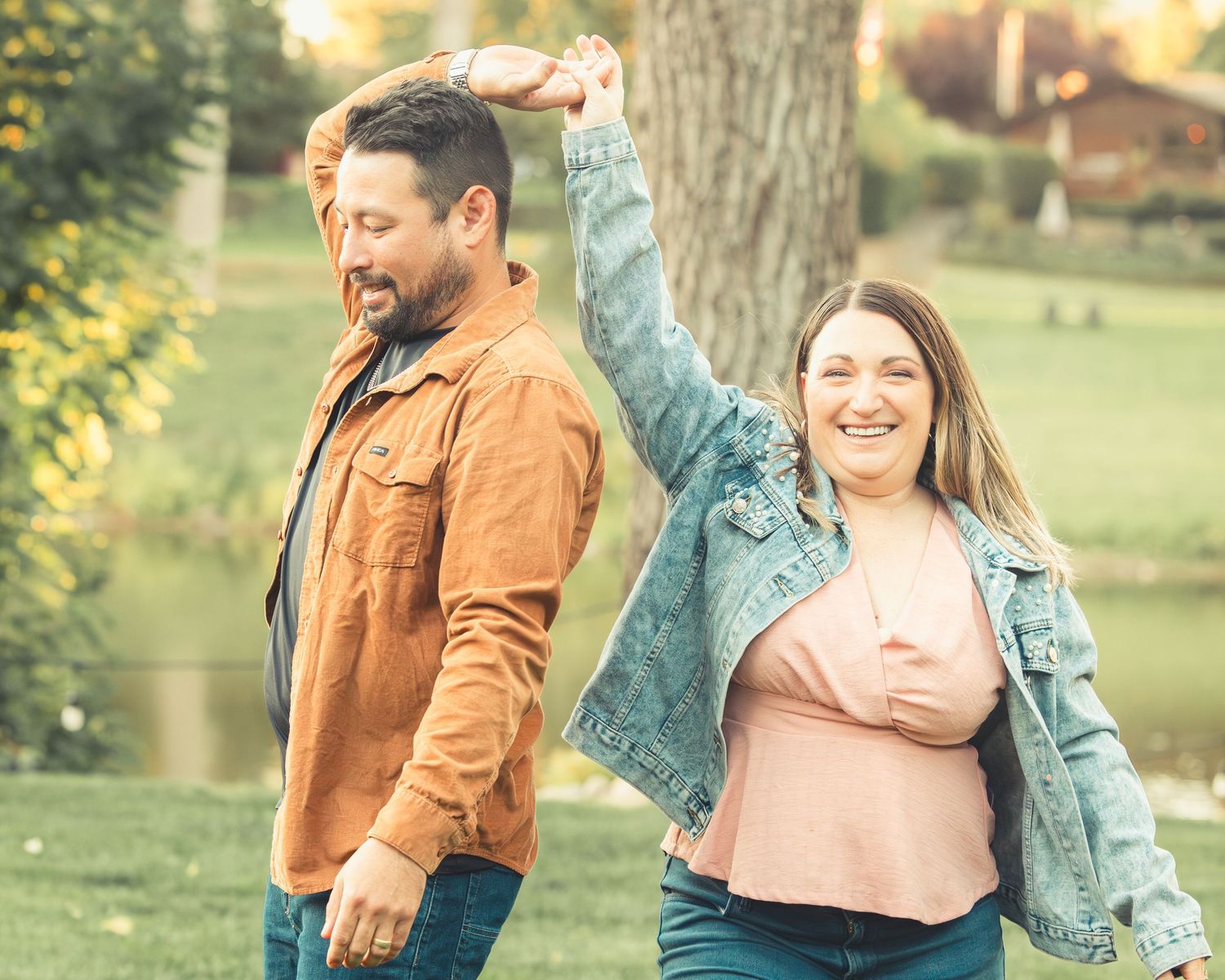 Joyful couple dancing outdoors in a park on a sunny autumn day.