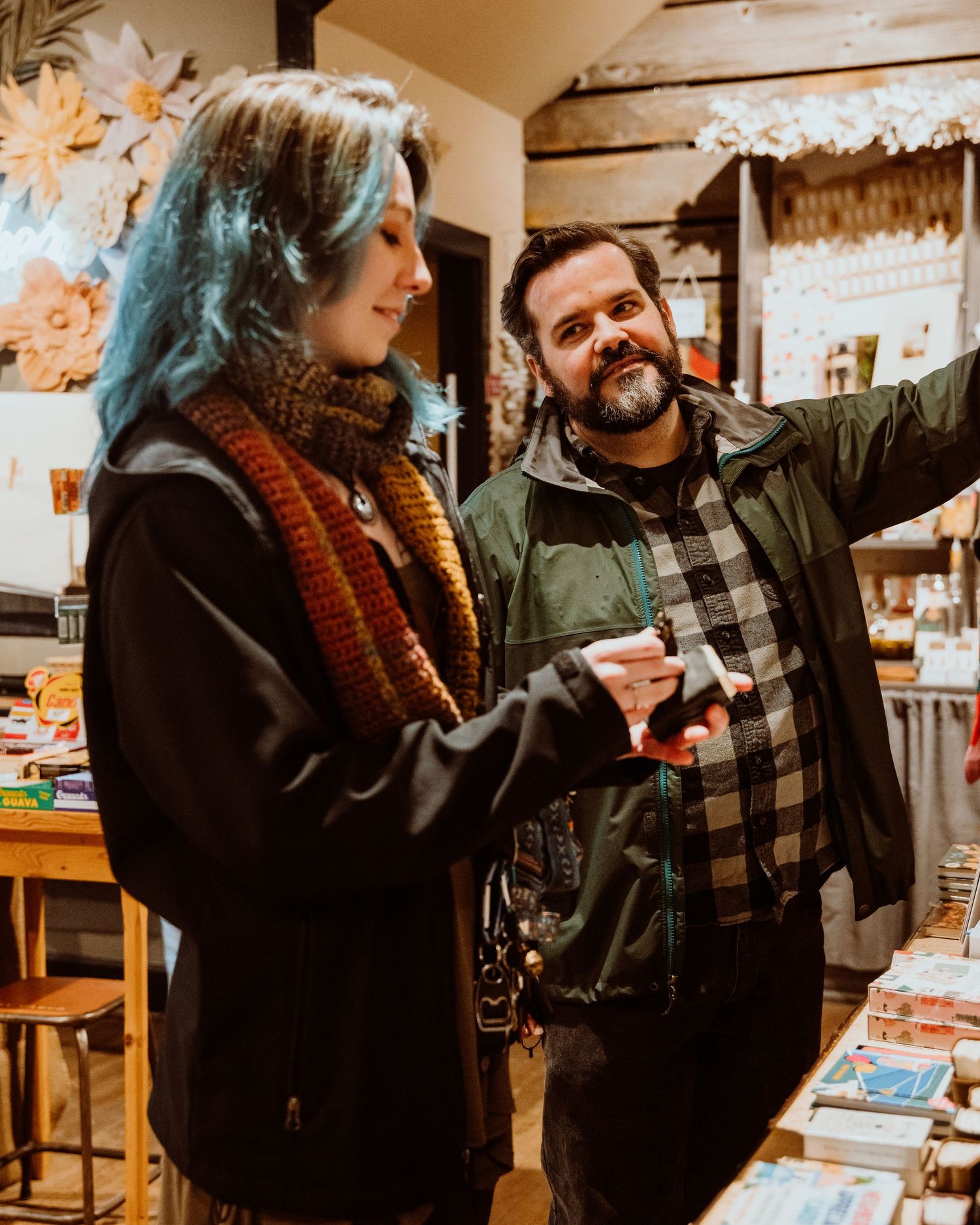 Man and woman with blue hair laughing together in a warm shop.