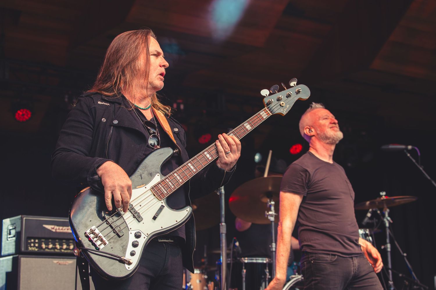 Bassist and vocalist performing energetically on stage at an outdoor rock concert.