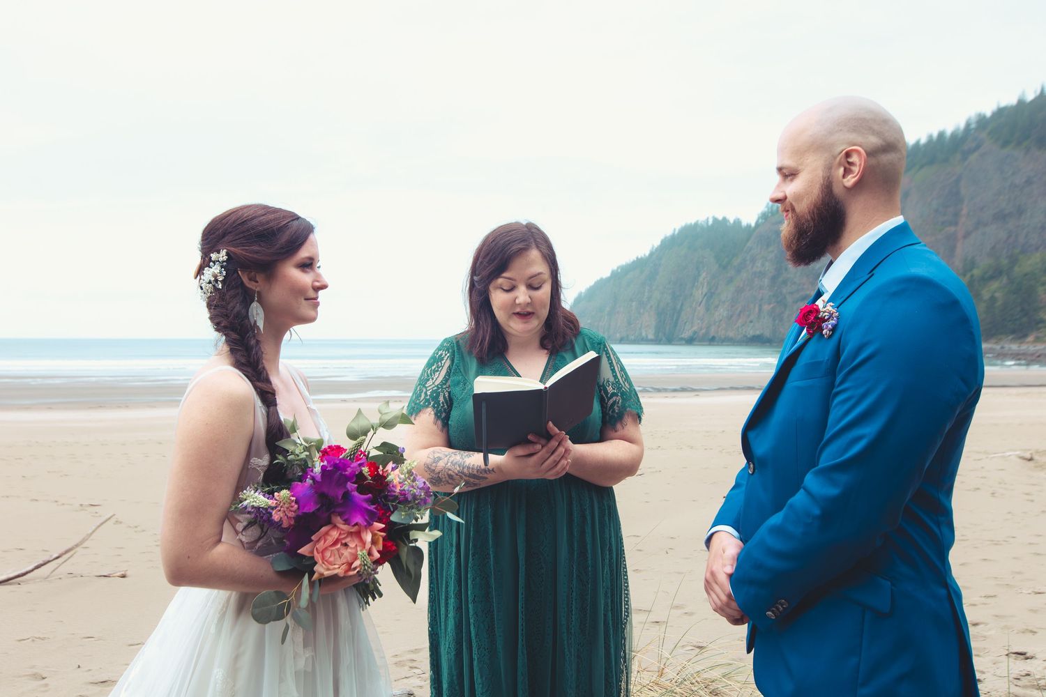 Bride and groom exchange vows with officiant on a sandy beach during an intimate outdoor wedding ceremony.
