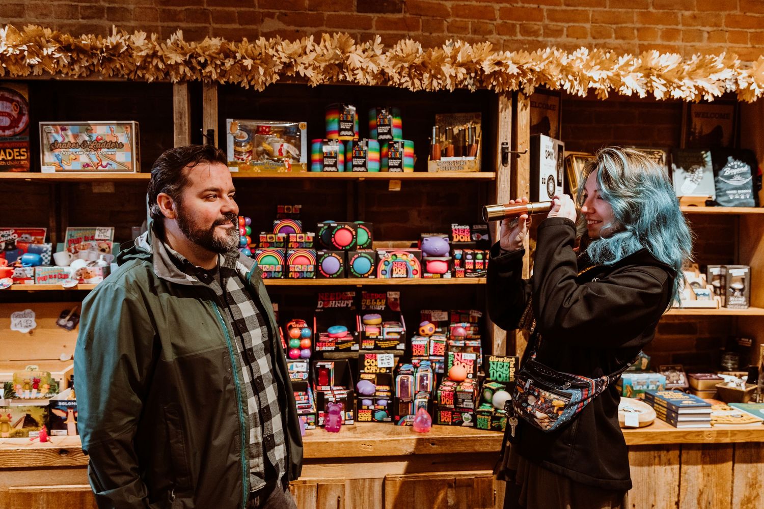 Blue-haired woman pointing at shelves while talking to a bearded man in a store.
