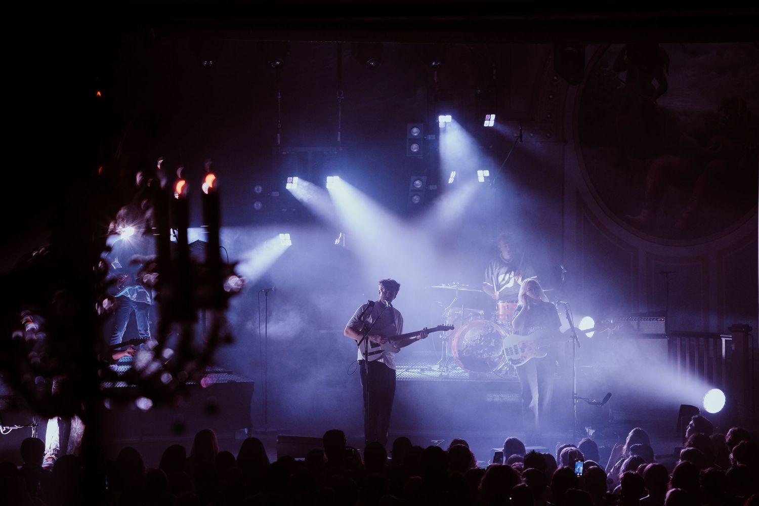 Band performs on stage with dramatic spotlight beams during live concert.