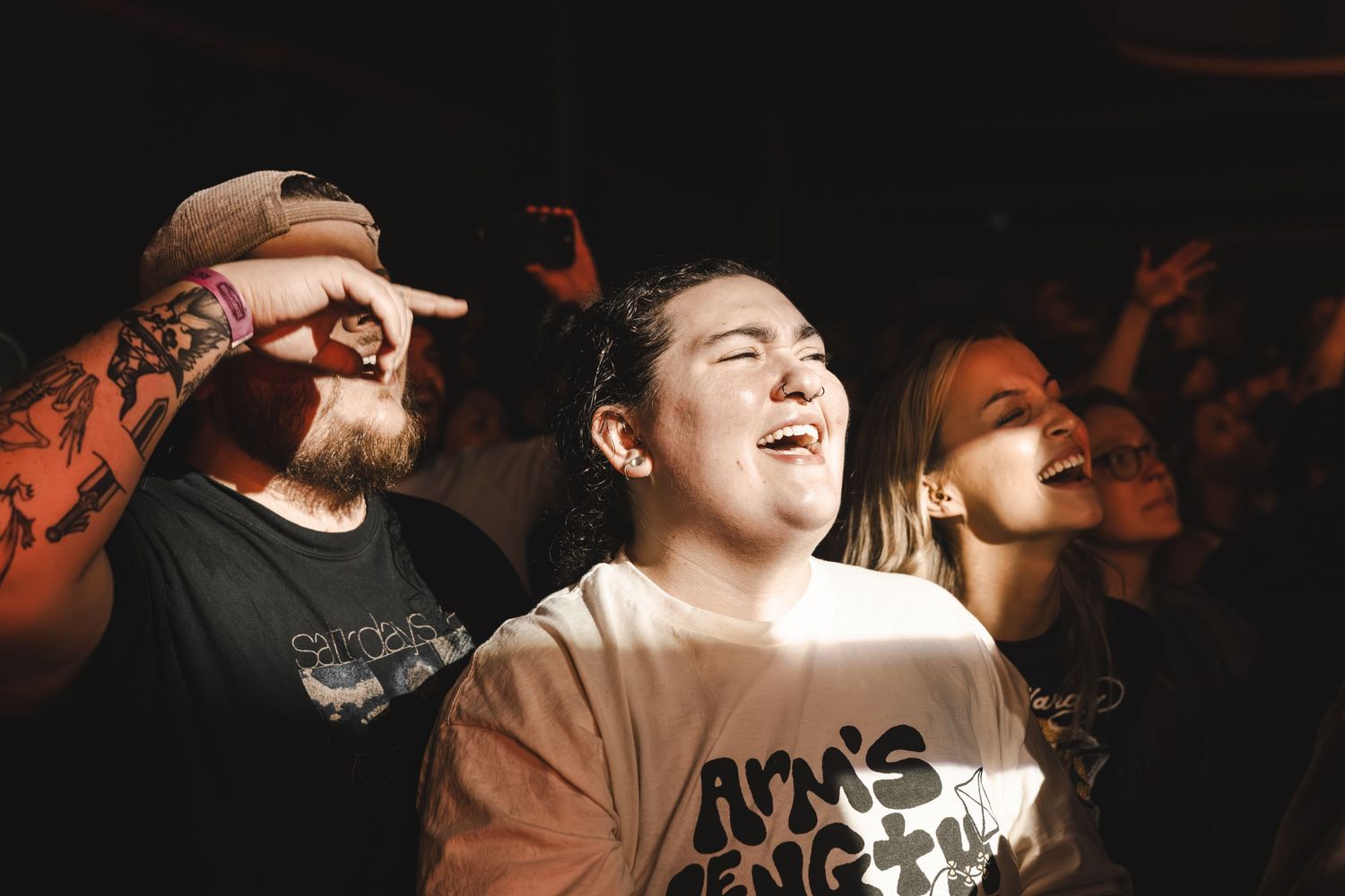 Excited concert crowd with woman singing along joyfully at an energetic live music event.