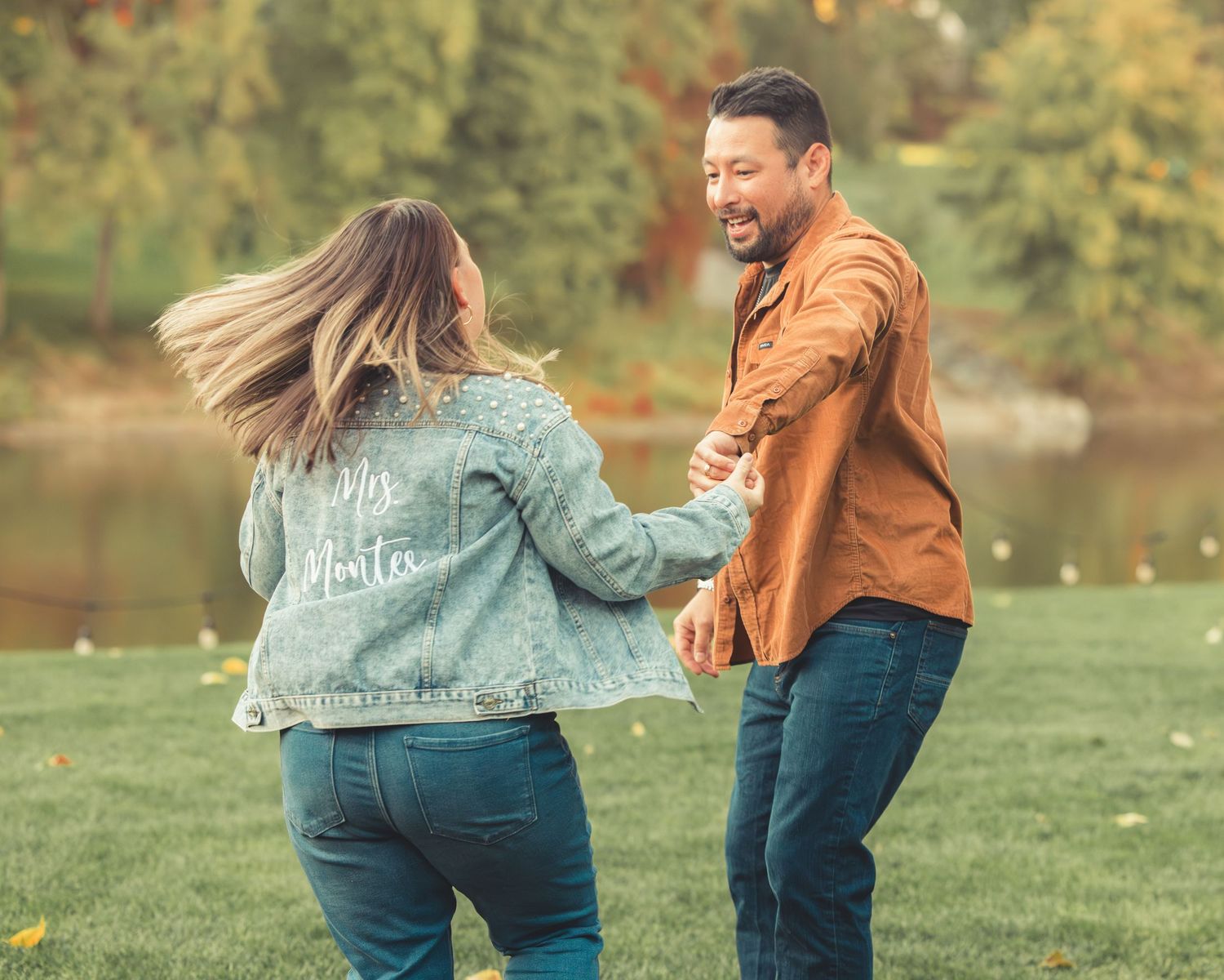 Couple dancing joyfully outdoors, woman wearing a custom denim jacket.