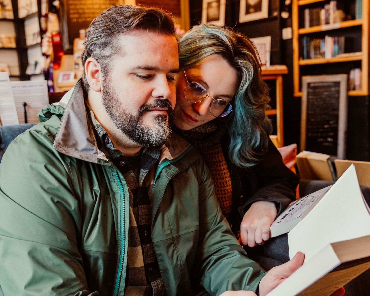 Couple reading a book together in a cozy bookstore cafe.