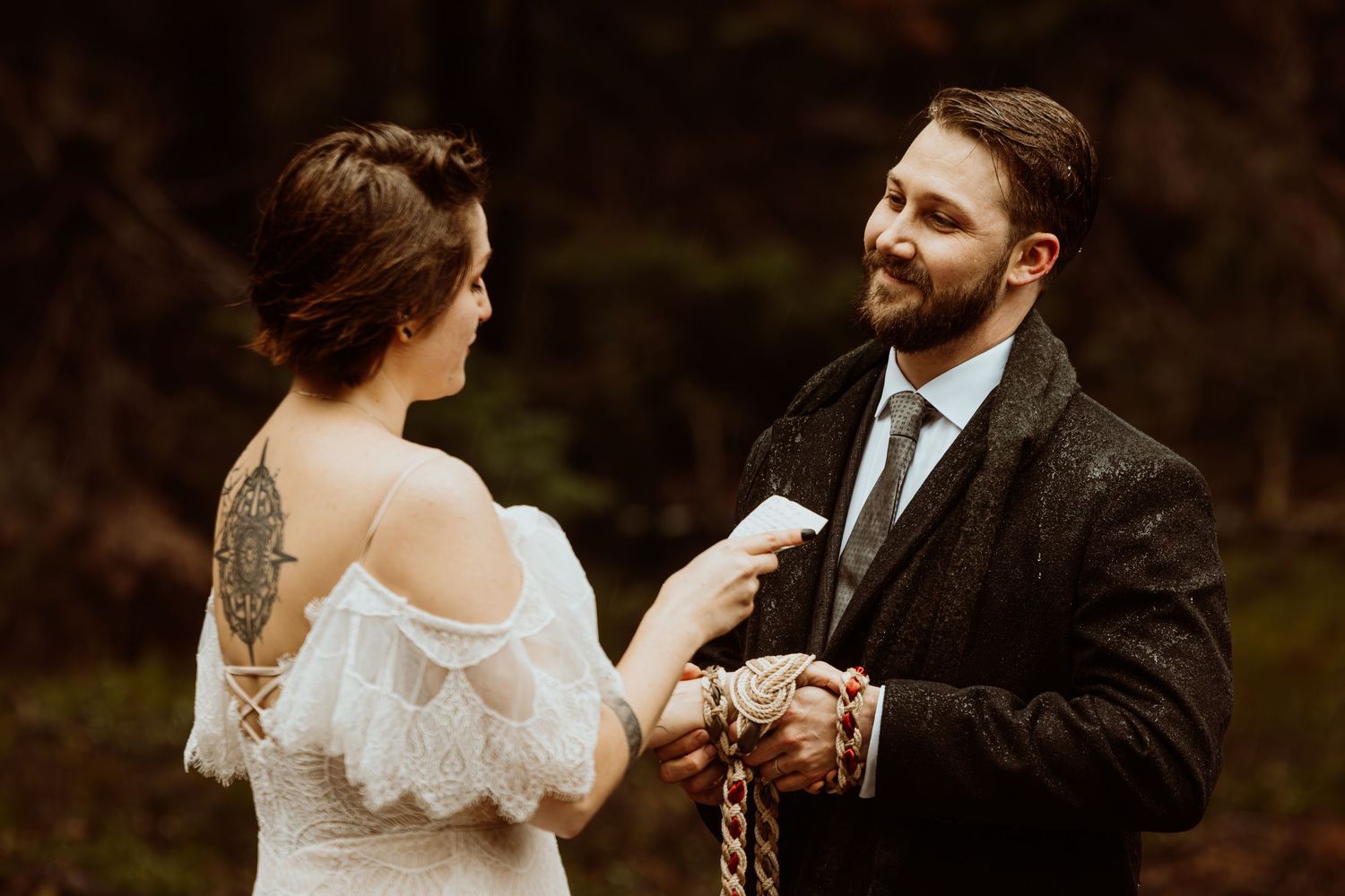 Couple shares a tender moment during a handfasting ceremony in an autumn forest setting.