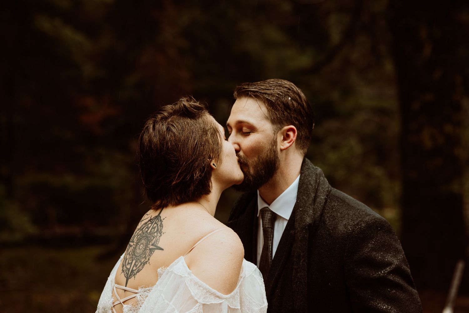 Bride and groom share their first kiss as a married couple in a romantic forest wedding.