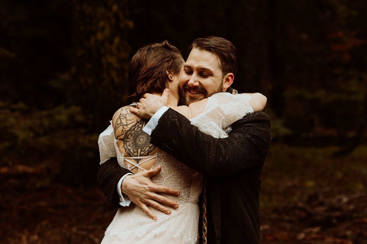 Bride and groom sharing a joyful embrace in a forest during their outdoor autumn wedding ceremony.
