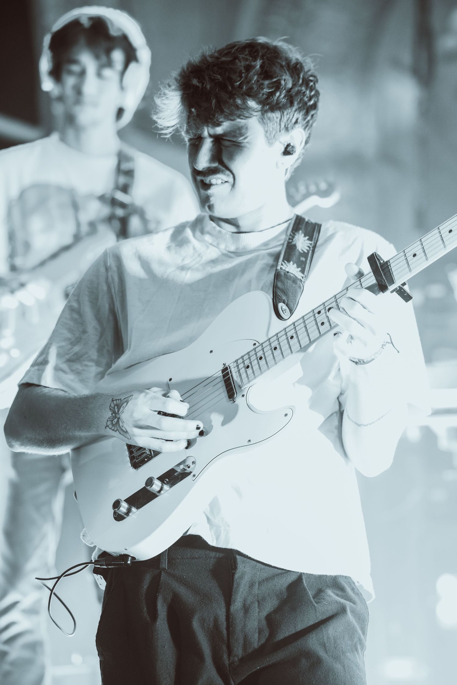 Young male guitarist plays electric guitar on stage during a live concert performance.