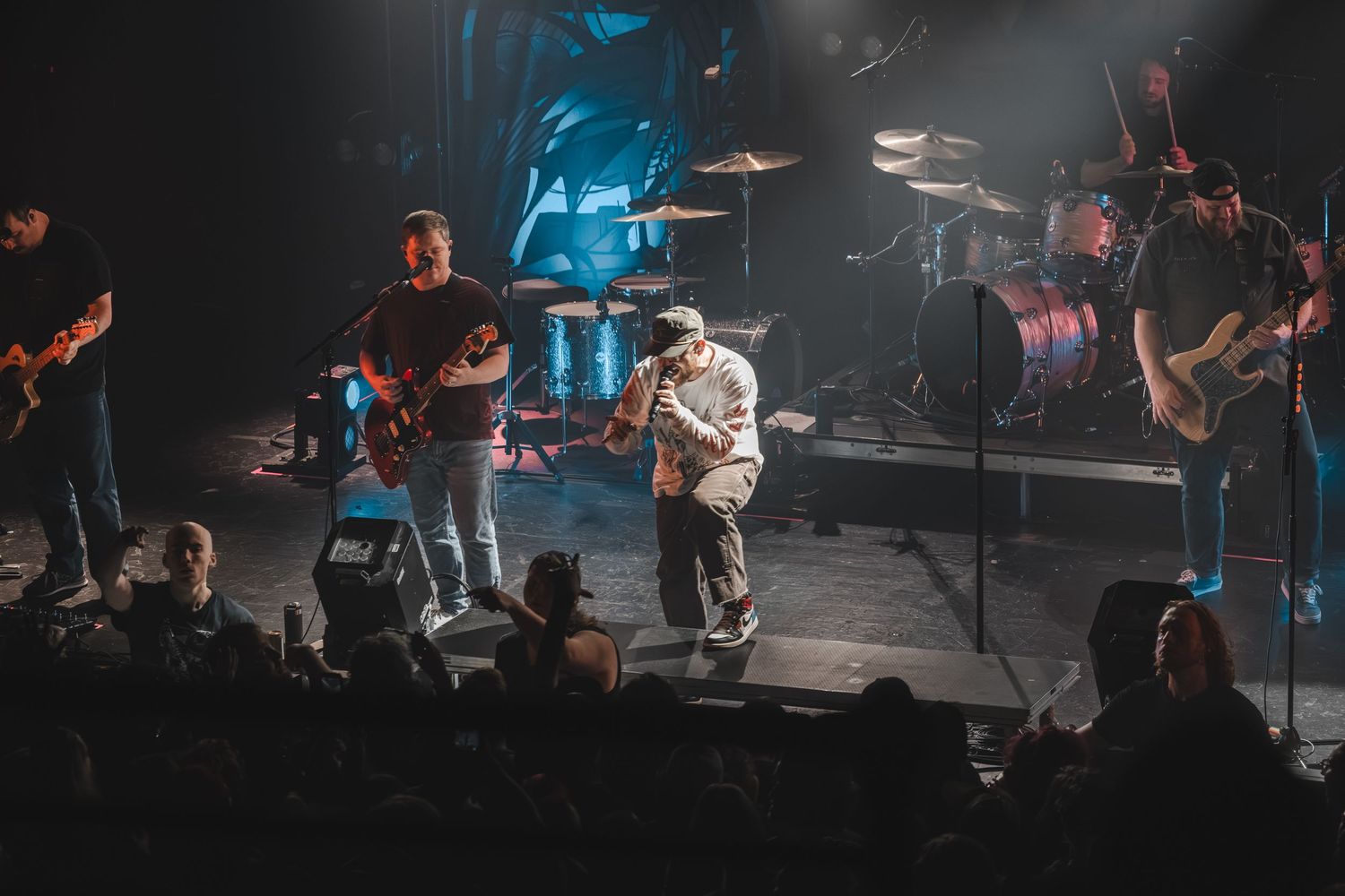 Live band performance on a colorful stage with guitarist and vocalist engaging the crowd.
