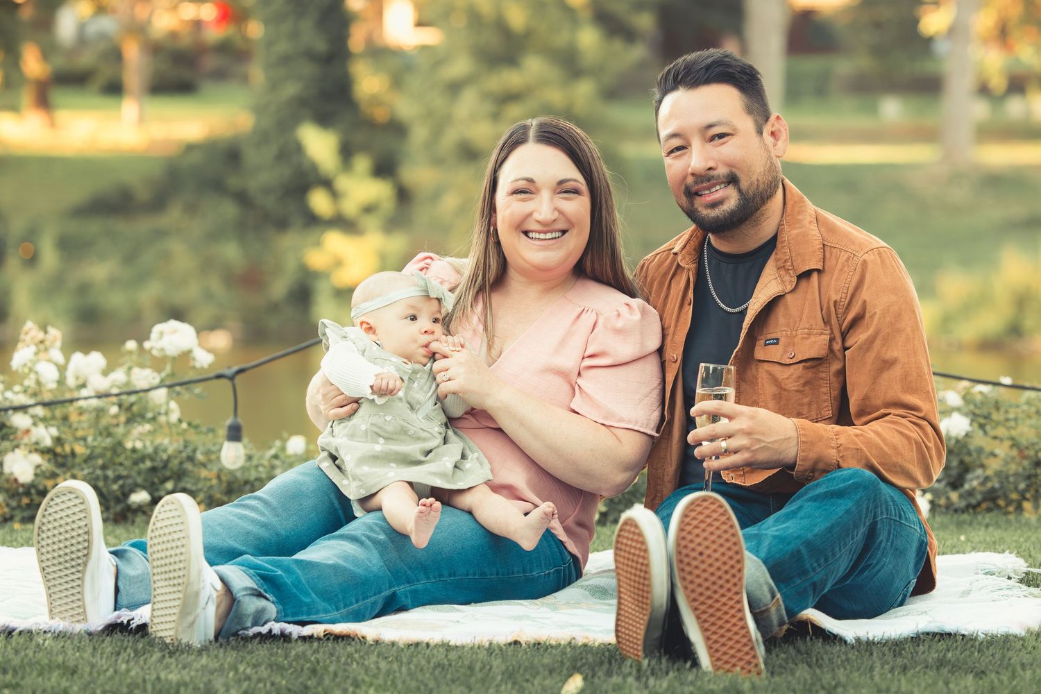 Happy family smiling with their baby during an outdoor park photoshoot.