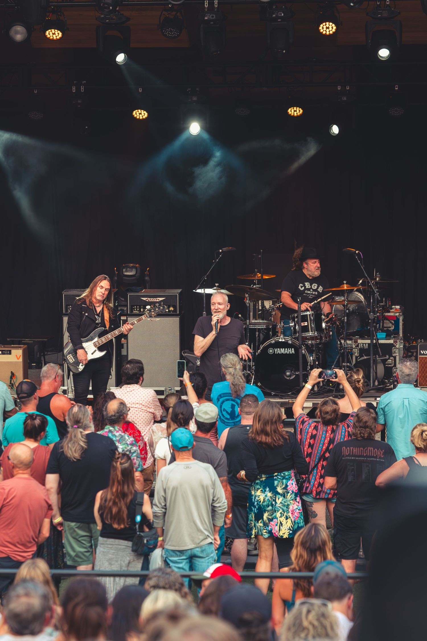 Rock band performing on an outdoor stage to an engaged festival crowd.