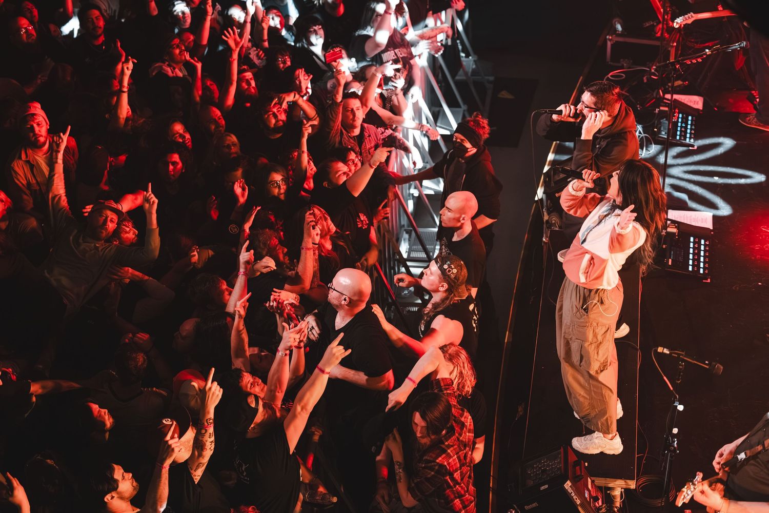 Singer interacts closely with fans in a crowded concert venue under colorful stage lights.