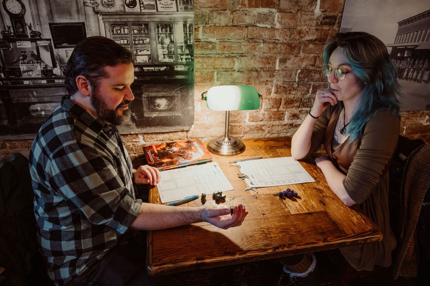 Man and woman sitting across from each other at a wooden table reviewing papers in a rustic bar.
