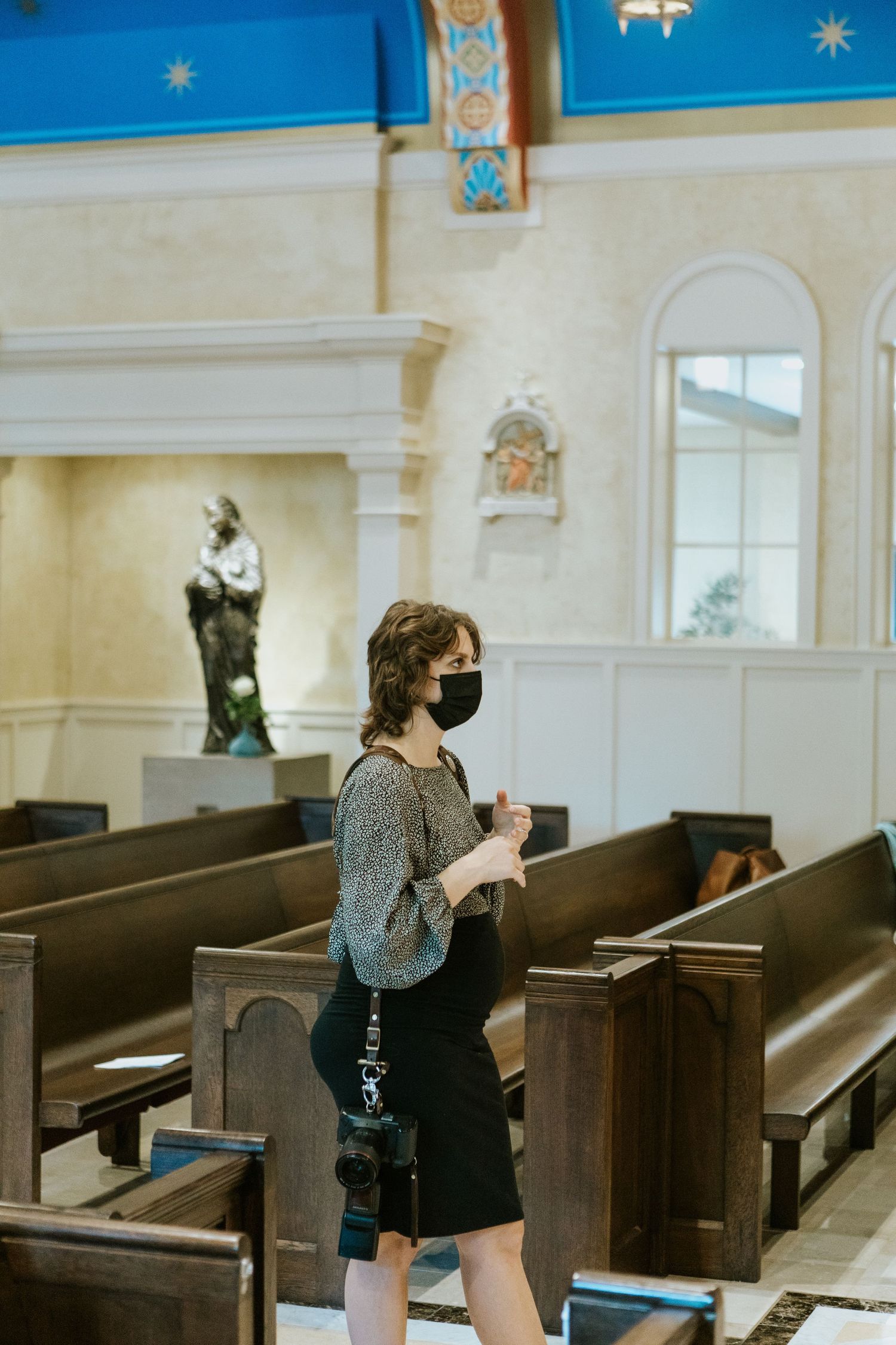 People sitting in wooden church pews in a bright white chapel interior.