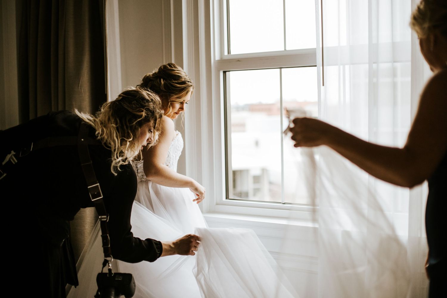 Silhouettes against bright windows during wedding preparation moments.