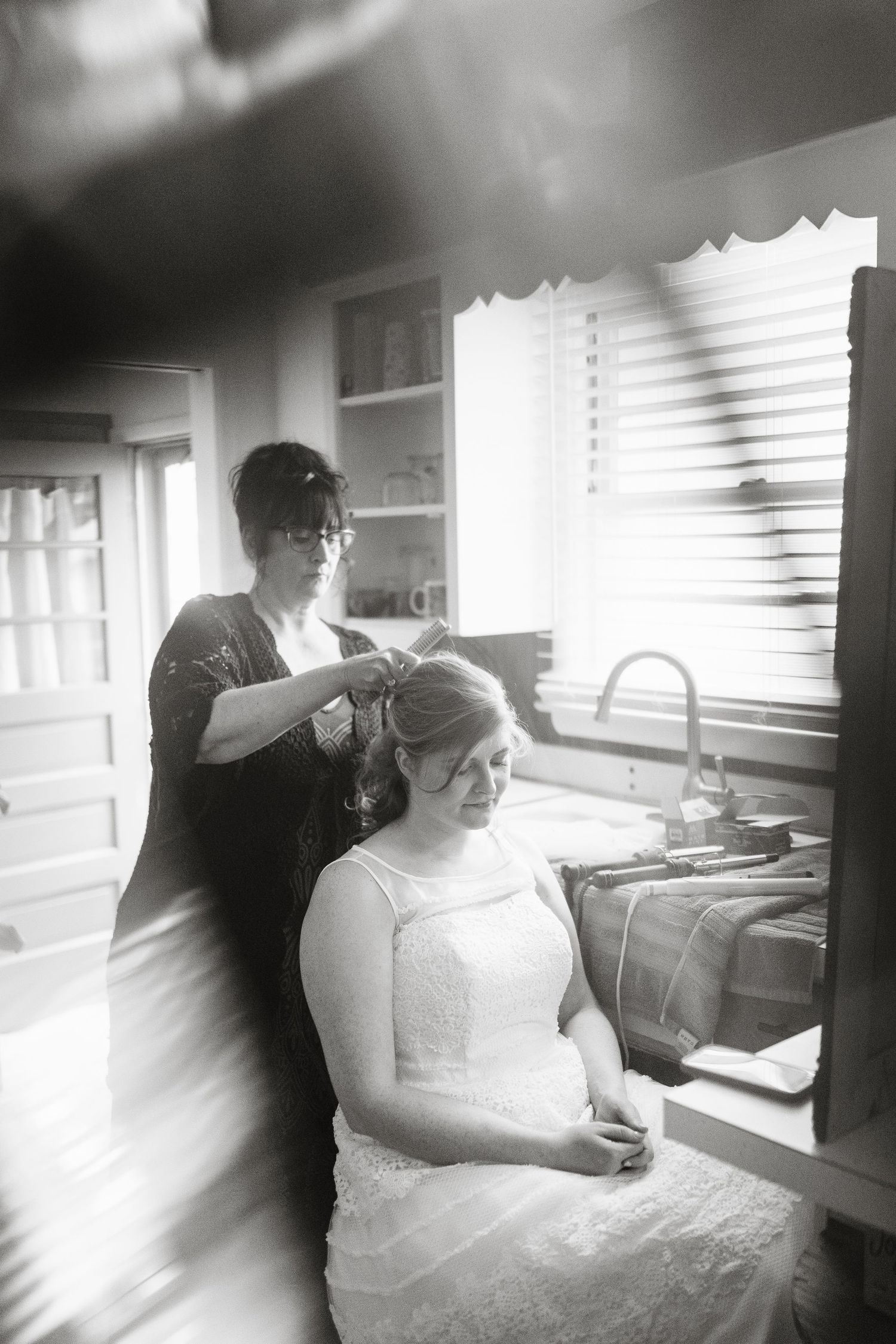 A black and white photo of wedding preparation in natural window light.