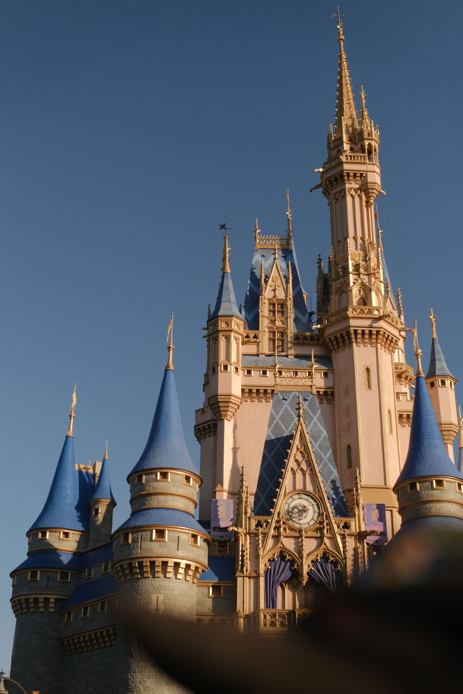 Cinderella Castle at Disney World photographed against clear blue sky during golden hour.