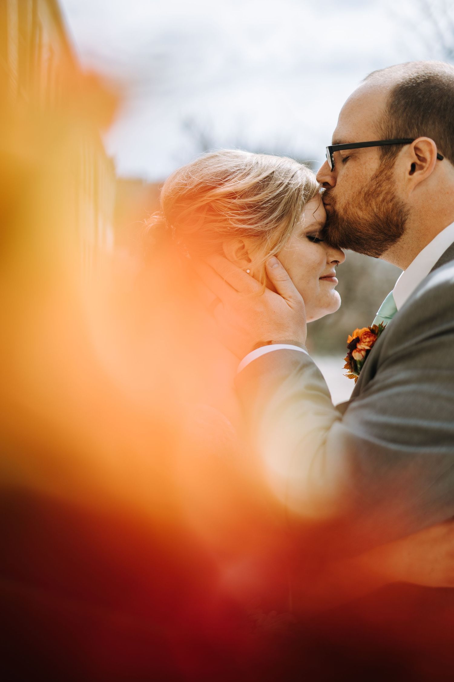 Romantic sunset wedding portrait with warm orange tones and soft bokeh lighting.