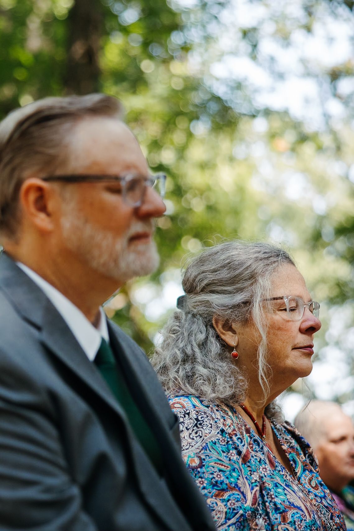Wedding guests seated outdoors watching the ceremony with attentive expressions.