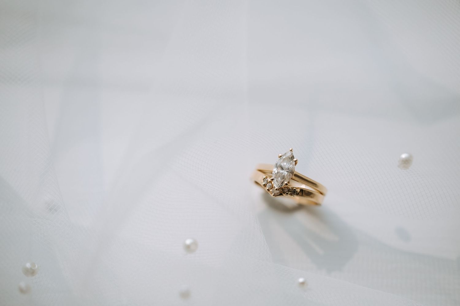 Gold wedding rings with diamonds photographed on white fabric.