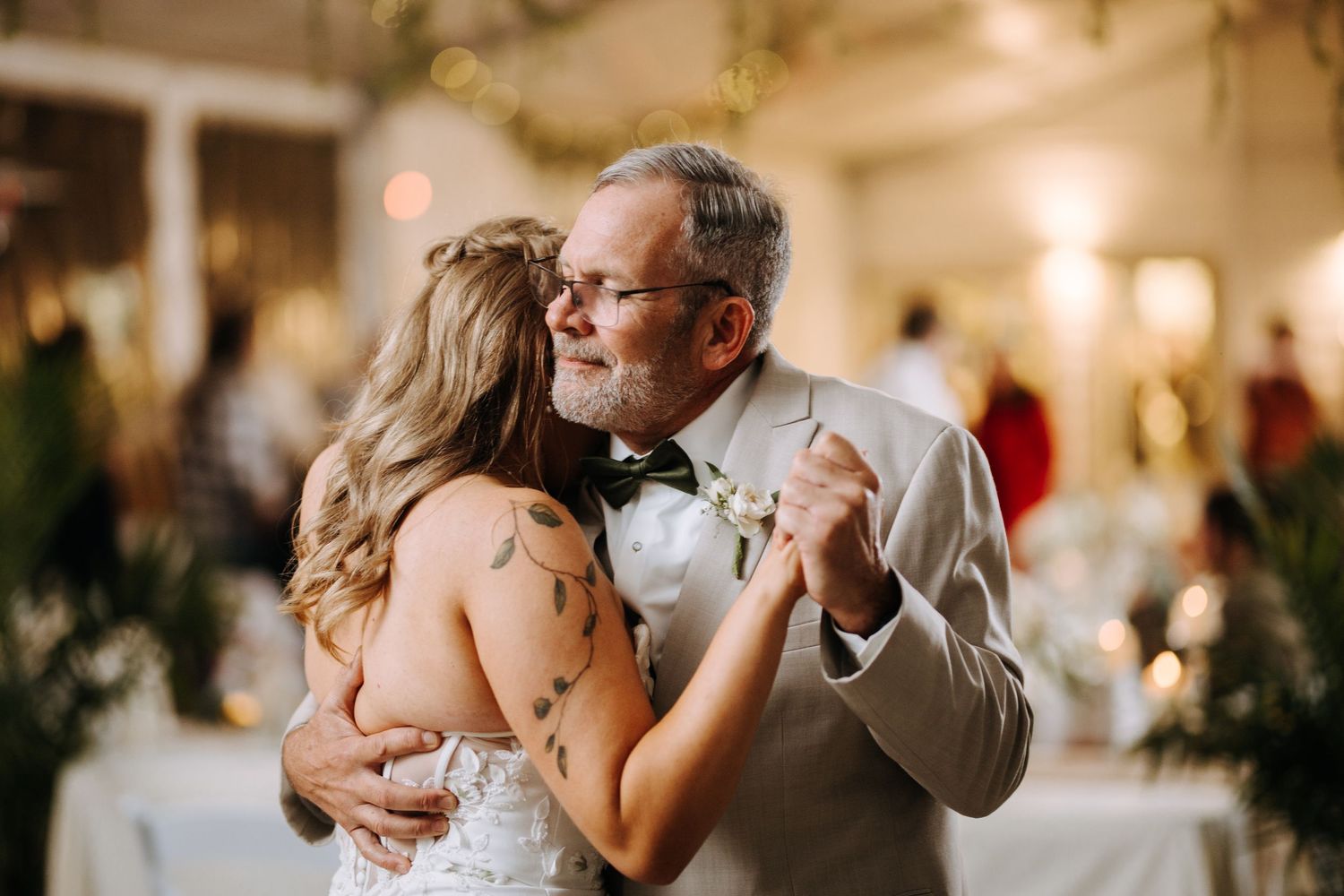 Couples slow dancing at an elegant indoor wedding reception with warm lighting.