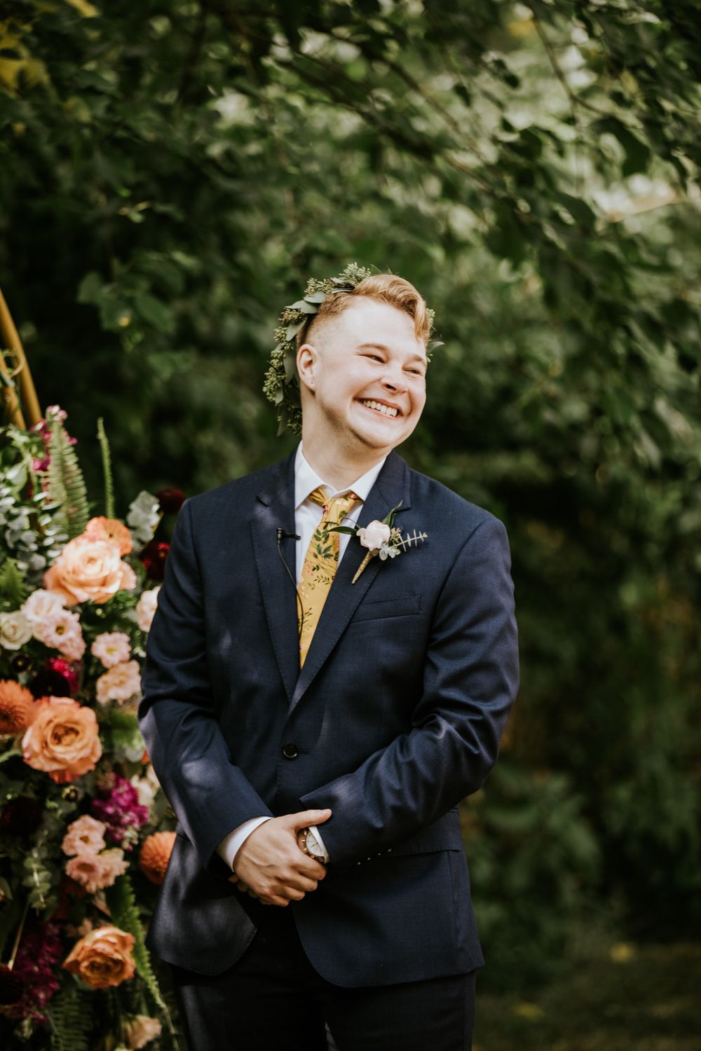 A joyful moment captured at an outdoor wedding ceremony with floral arrangements of peach and pink blooms.